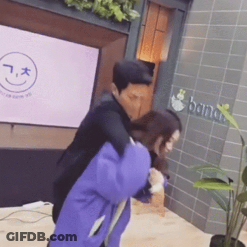 A Man Is Carrying A Woman On His Back In Front Of A Building . GIF