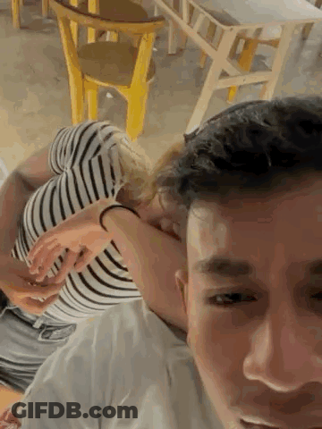 A Man Is Carrying A Woman On His Shoulders In A Room . GIF