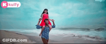A Man Is Carrying A Woman On His Shoulders On The Beach GIF