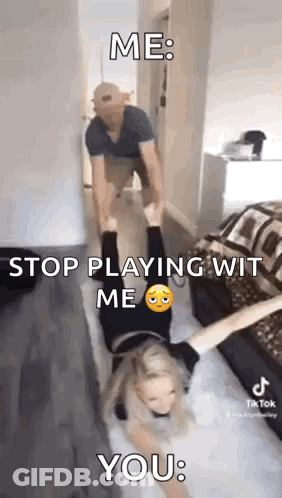A Man Is Carrying A Woman Upside Down On His Shoulders In A Room . GIF