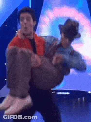 A Man Is Carrying Another Man In His Arms GIF