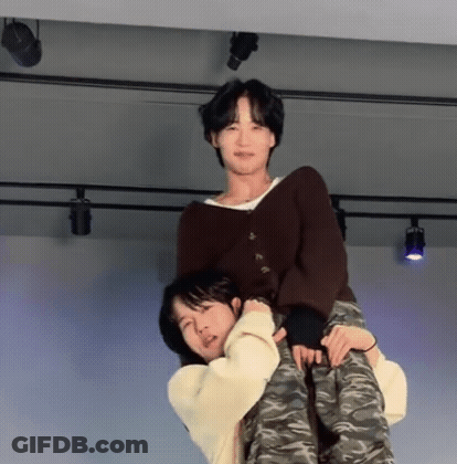 A Man Is Carrying Another Man On His Back On A Stage . GIF