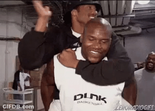 A Man Is Carrying Another Man On His Shoulders In A Basketball Court . GIF