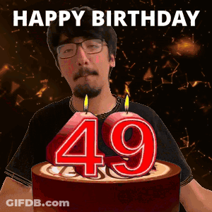 A Man Is Celebrating His 49Th Birthday With A Cake With Candles In The Shape Of The Number 49 GIF