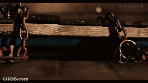 A Man Is Chained To A Wooden Plank With A X On The Bottom Right GIF
