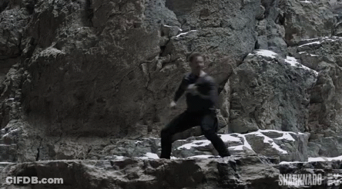 A Man Is Climbing A Rock Wall With The Words Sharknado On The Bottom Right GIF