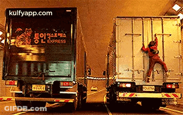 A Man Is Climbing On The Back Of A Semi Truck . GIF