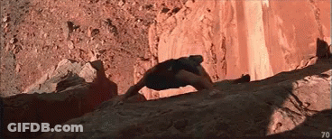 A Man Is Climbing Up A Rocky Cliff With The Number 70 In The Corner . GIF