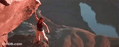 A Man Is Climbing Up The Side Of A Rocky Mountain . GIF