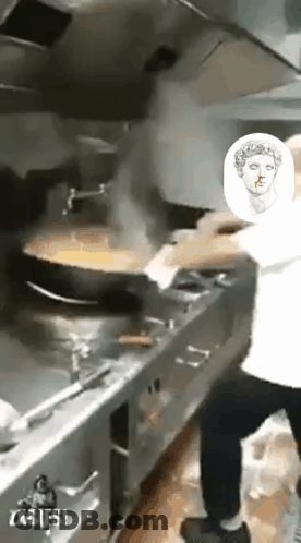 A Man Is Cooking Food In A Kitchen With A Picture Of A Statue Of A Woman On The Wall . GIF