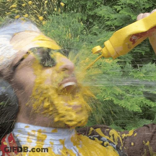A Man Is Covered In Mustard While Holding A Bottle GIF