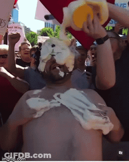 A Man Is Covered In Whipped Cream While Holding A Bucket In His Hand GIF