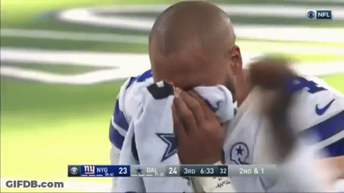 A Man Is Covering His Face With A Towel While Watching A Football Game . GIF