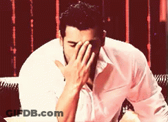 A Man Is Covering His Face With His Hand GIF