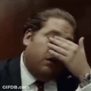 A Man Is Covering His Face With His Hand . GIF