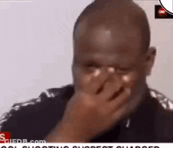 A Man Is Covering His Face With His Hand While Crying . GIF