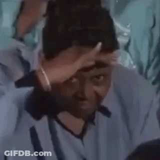 A Man Is Covering His Face With His Hand While Sitting In A Crowd Of People . GIF