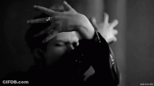 A Man Is Covering His Face With His Hands In A Black And White Photo . GIF