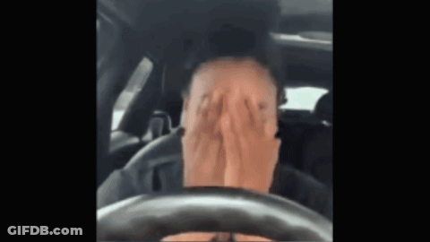 A Man Is Covering His Face With His Hands While Driving A Car . GIF