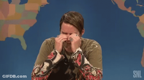 A Man Is Covering His Face With His Hands While Sitting In Front Of A Map Of The United States . GIF