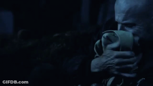 A Man Is Covering His Mouth With A Napkin In The Dark . GIF