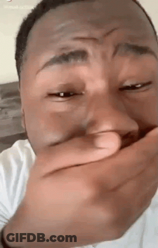 A Man Is Covering His Mouth With His Hand While Laughing . GIF