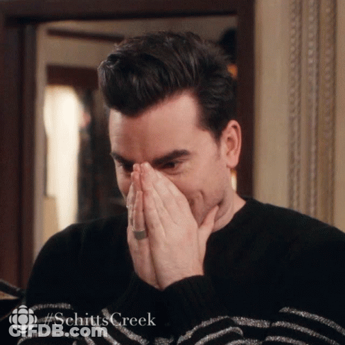 A Man Is Covering His Mouth With His Hands And The Word Schitts Creek Is On The Bottom Right GIF