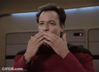 A Man Is Covering His Mouth With His Hands While Wearing A Red Shirt . GIF