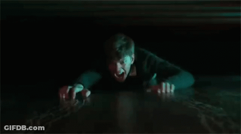 A Man Is Crawling Out Of A Hole In The Floor In The Dark . GIF