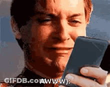 A Man Is Crying While Holding A Cell Phone And Making A Funny Face . GIF