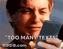 A Man Is Crying While Holding A Cell Phone And Says `` Too Many Texts '' . GIF