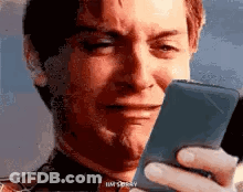 A Man Is Crying While Holding A Cell Phone . GIF