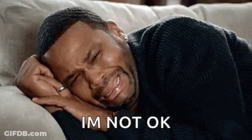 A Man Is Crying While Laying On A Couch And Saying `` Im Not Ok '' . GIF