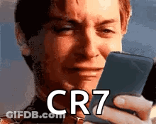 A Man Is Crying While Looking At A Cell Phone With The Word Cr7 On It . GIF