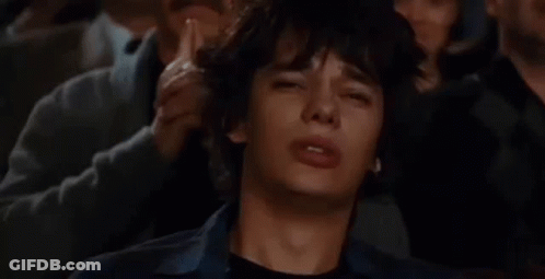 A Man Is Crying While Sitting In A Crowd Of People Watching A Movie . GIF