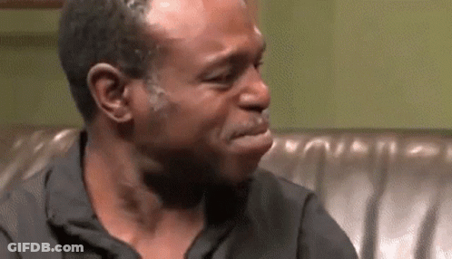 A Man Is Crying While Sitting On A Couch And Making A Funny Face . GIF