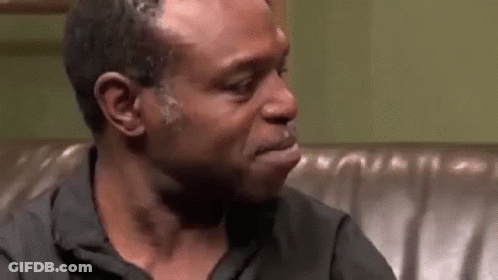 A Man Is Crying While Sitting On A Couch In A Room . GIF