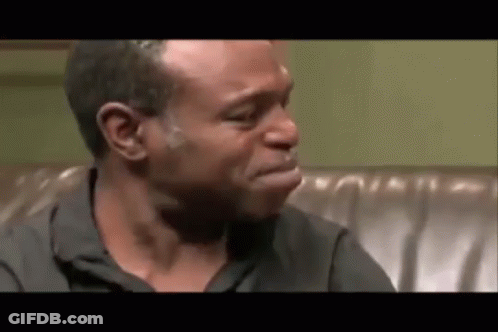 A Man Is Crying While Sitting On A Couch With His Mouth Open . GIF