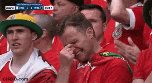 A Man Is Crying While Watching A Soccer Game In A Crowd . GIF