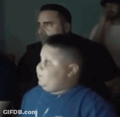 A Man Is Cutting A Boy 'S Hair In A Barber Shop . GIF