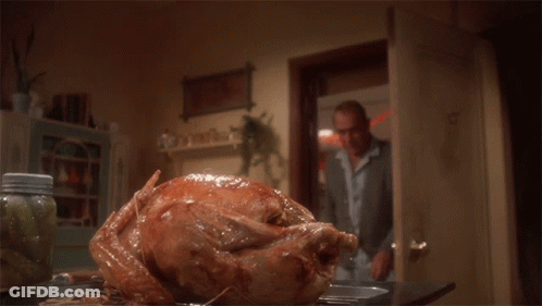 A Man Is Cutting A Large Turkey On A Table GIF