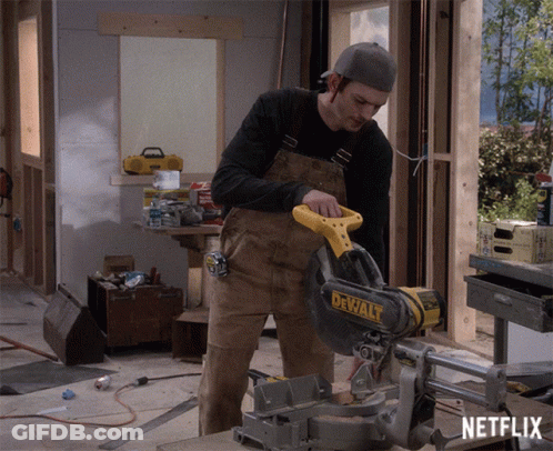 A Man Is Cutting A Piece Of Wood With A Dewalt Circular Saw GIF