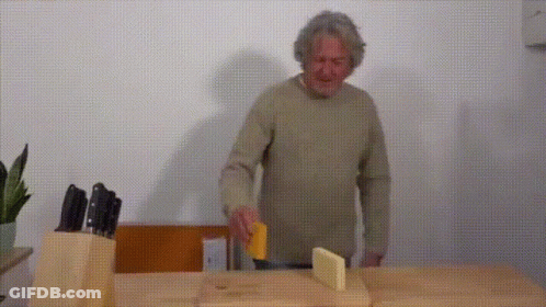 A Man Is Cutting Cheese On A Cutting Board GIF
