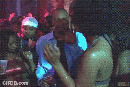 A Man Is Dancing In A Club While Holding A Drink . GIF