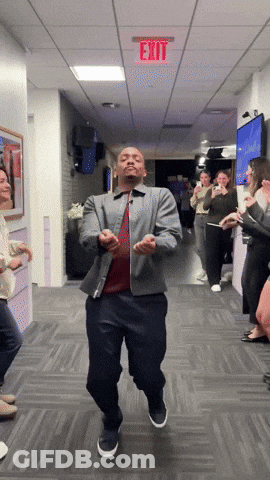 A Man Is Dancing In A Hallway With A Red Exit Sign Above Him GIF