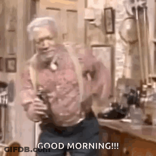 A Man Is Dancing In A Kitchen With A Bottle Of Beer In His Hand . GIF