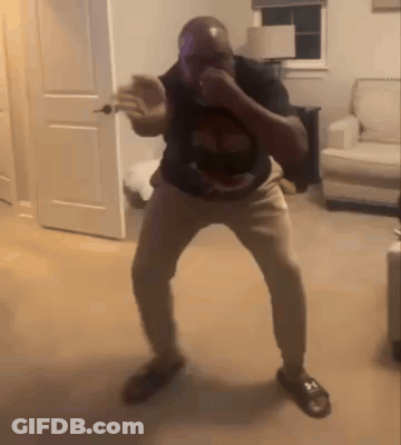 A Man Is Dancing In A Living Room In Front Of A Couch And A Door . GIF