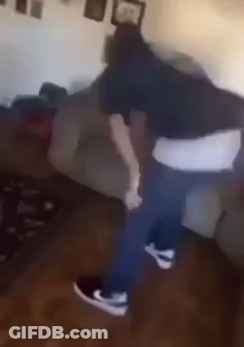 A Man Is Dancing In A Living Room Next To A Couch . GIF