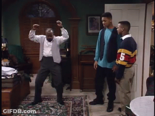 A Man Is Dancing In A Living Room While Two Other Men Stand Behind Him . GIF