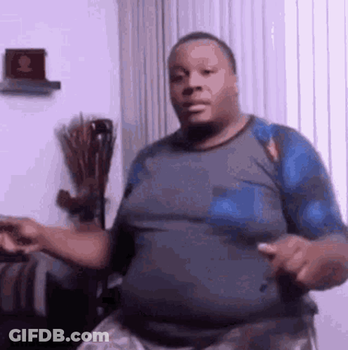 A Man Is Dancing In A Living Room While Wearing A Blue Shirt . GIF